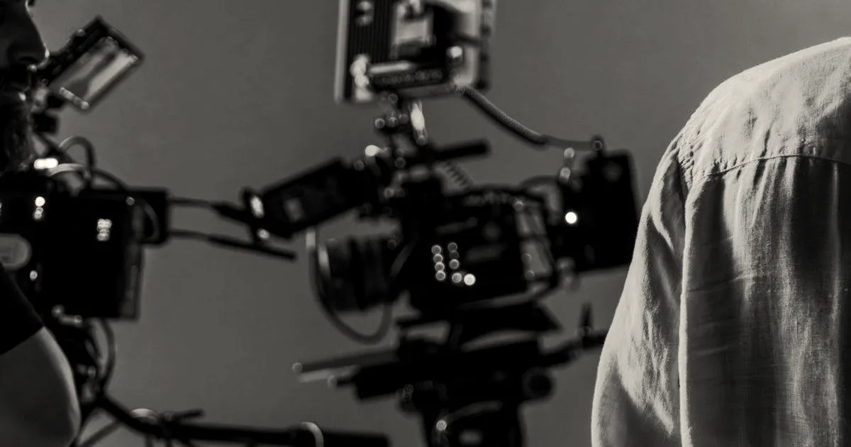A professional cinema camera on a movie production set with studio crew and lighting equipment.