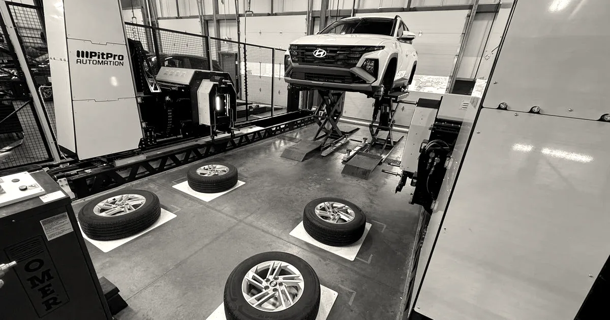 A Hyundai car raised on a lift inside a workshop with PitPro automated tire-changing equipment nearby.