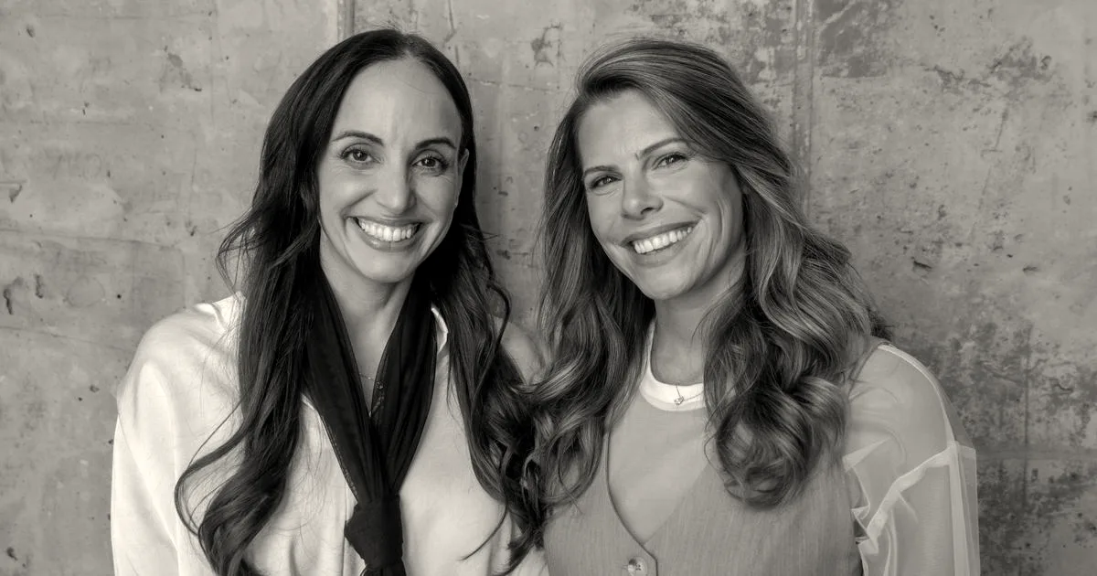 Portrait of Protego Ventures founders Lee Moser and Lital Leshem smiling together against a concrete wall