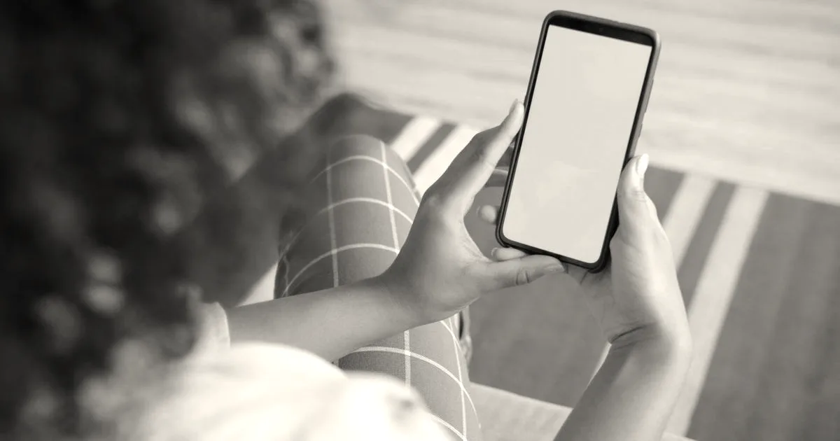 Close-up of a woman using a smartphone with a green screen for mockup indoors.