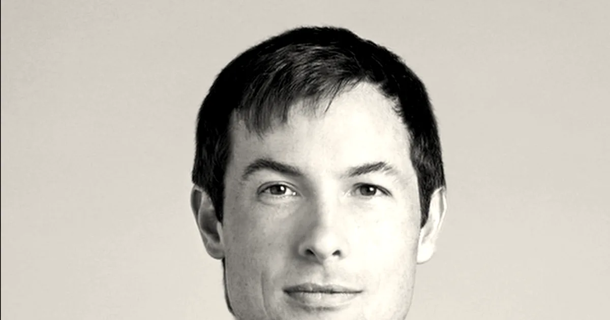 Black and white portrait of Reed Jobs looking slightly to the side in a dark t-shirt.