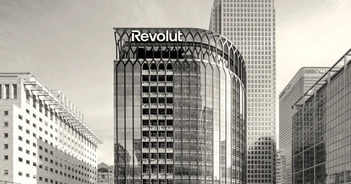 Exterior view of the Revolut headquarters building in London with brand signage on top against blue sky.