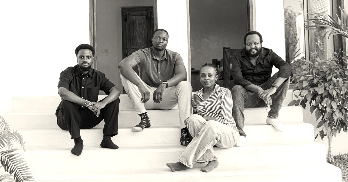 Four members of the Satlyt team sitting on outdoor steps in front of an entrance.