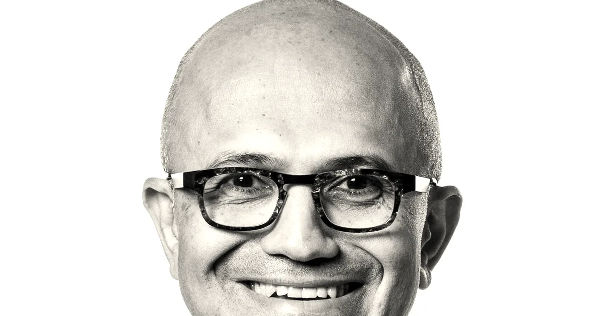 Portrait of Microsoft CEO Satya Nadella smiling while wearing glasses and a dark blazer.