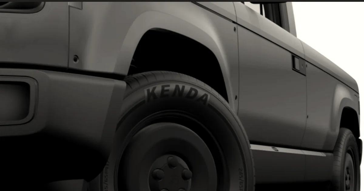Close-up view of the front wheel and side panel of a bright pink Slate Auto EV truck.