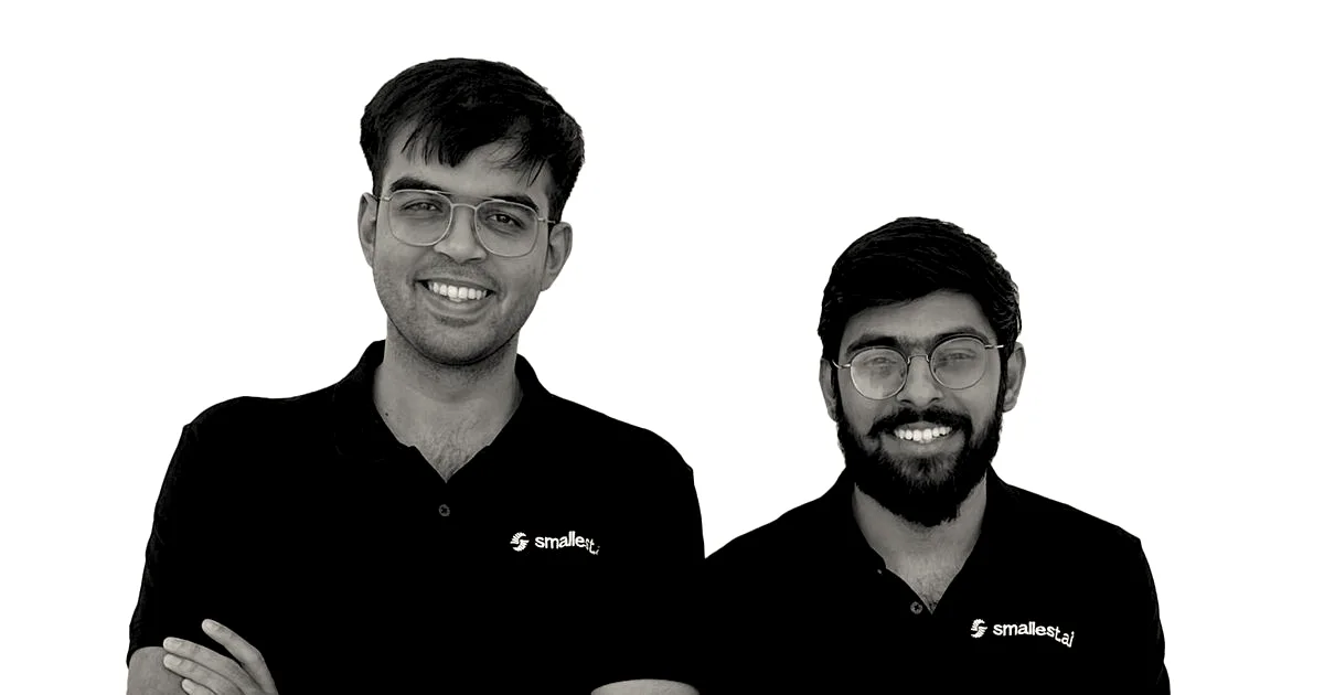 Two founders of Smallest.ai smiling while standing side by side wearing black polo shirts with arms crossed.