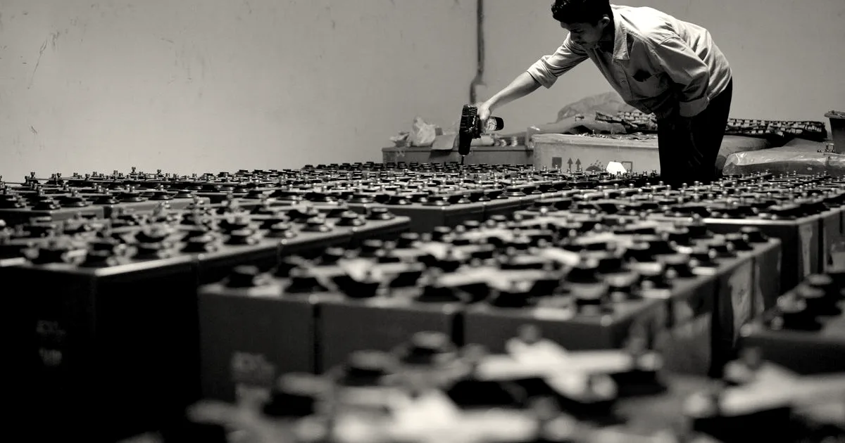 A technician assembling large industrial battery storage units inside a commercial energy facility