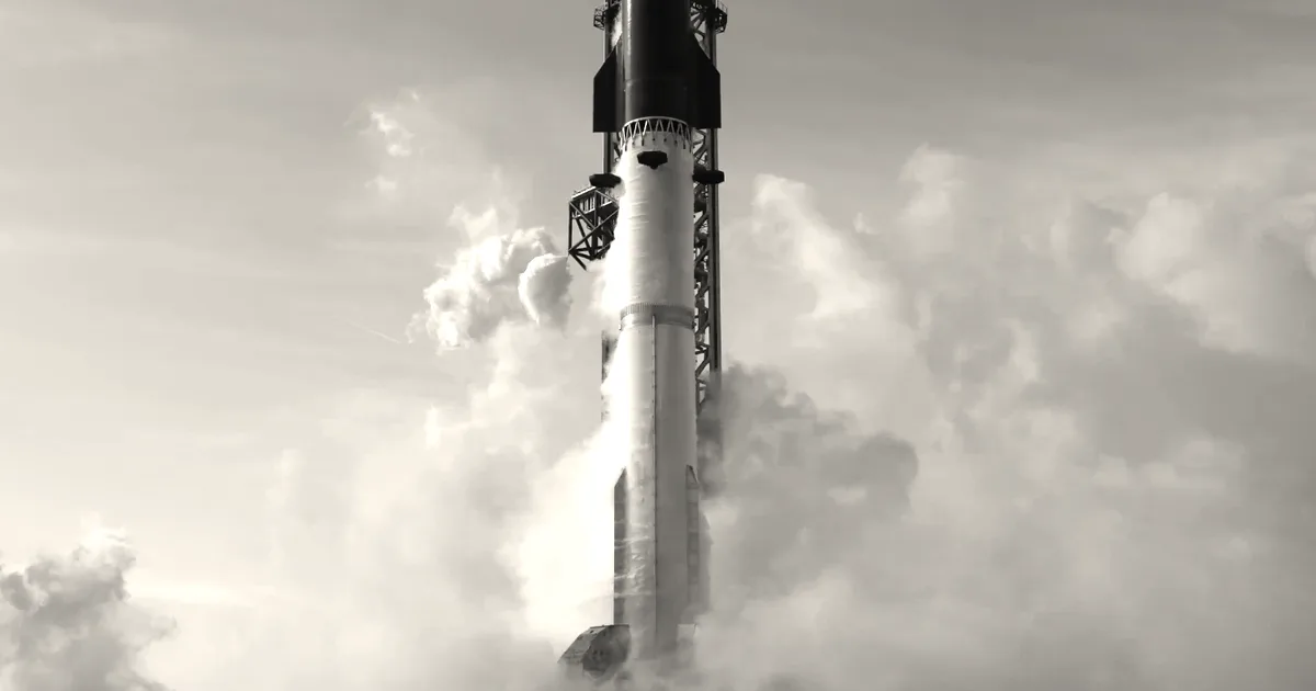 A large SpaceX rocket on a launch pad surrounded by smoke against a blue sky.