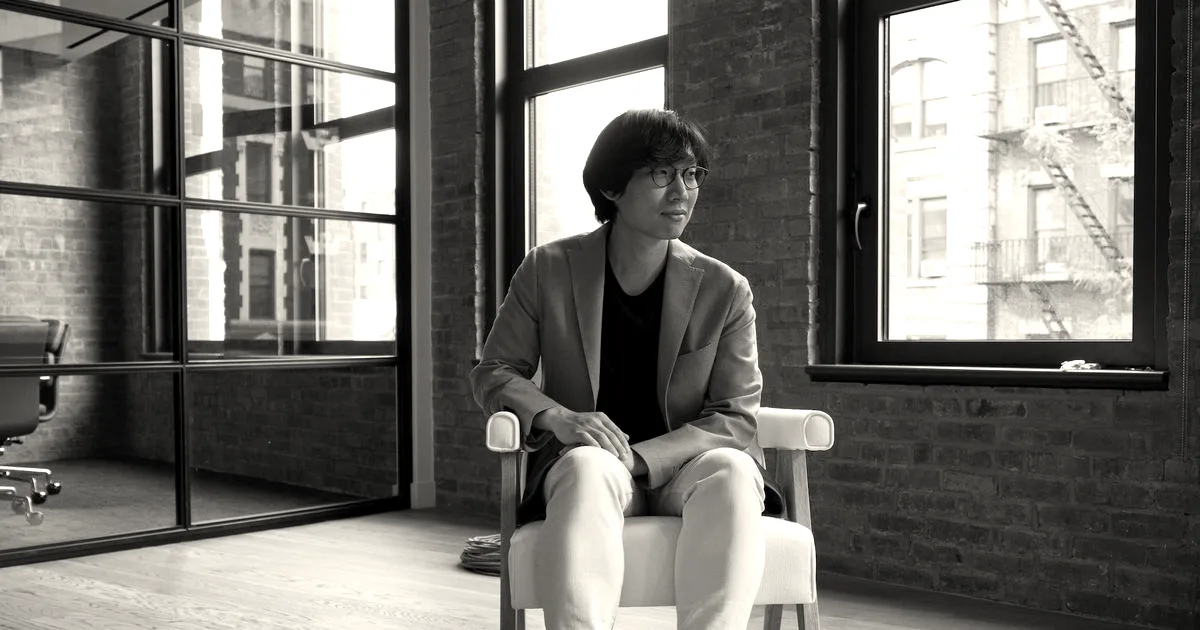 Founder and CEO Joon Sung Park sitting in a modern office chair, wearing a blazer and light pants.