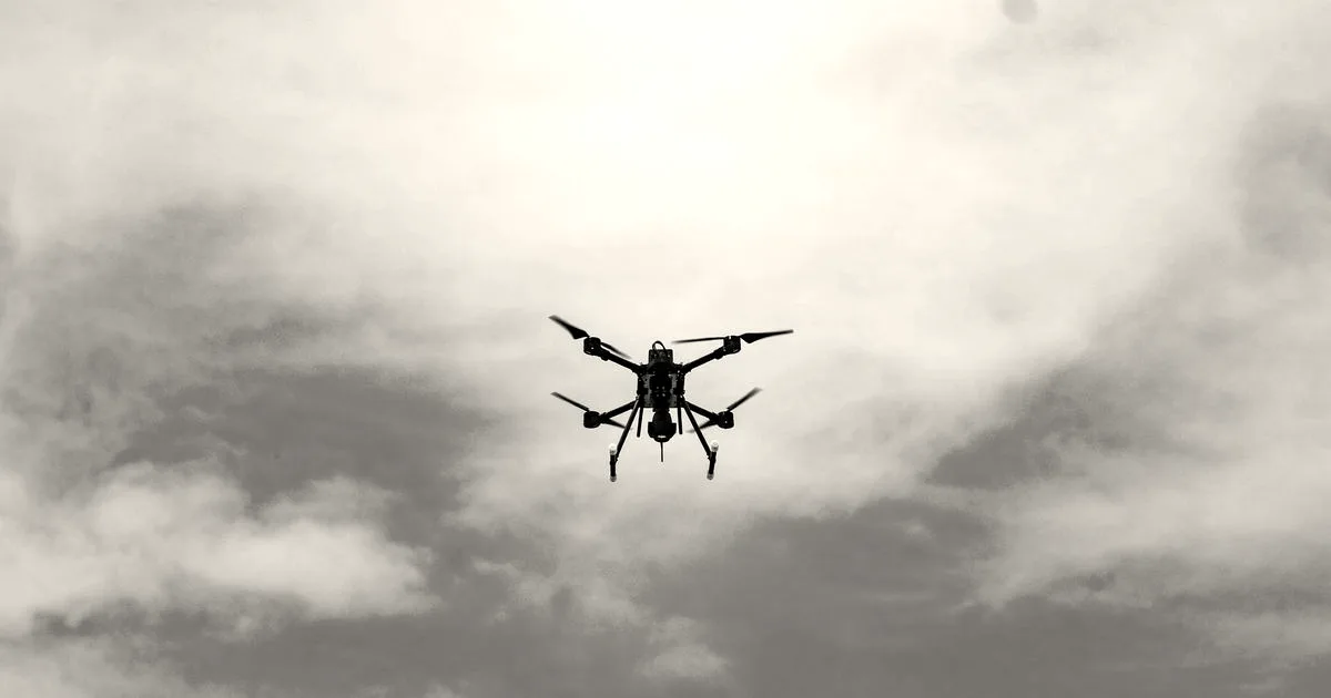 A black multi-rotor drone built by Terra Industries flying against a blue sky with light clouds.