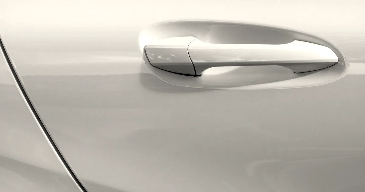 Close-up of a modern flush white exterior car door handle set into the vehicle body.