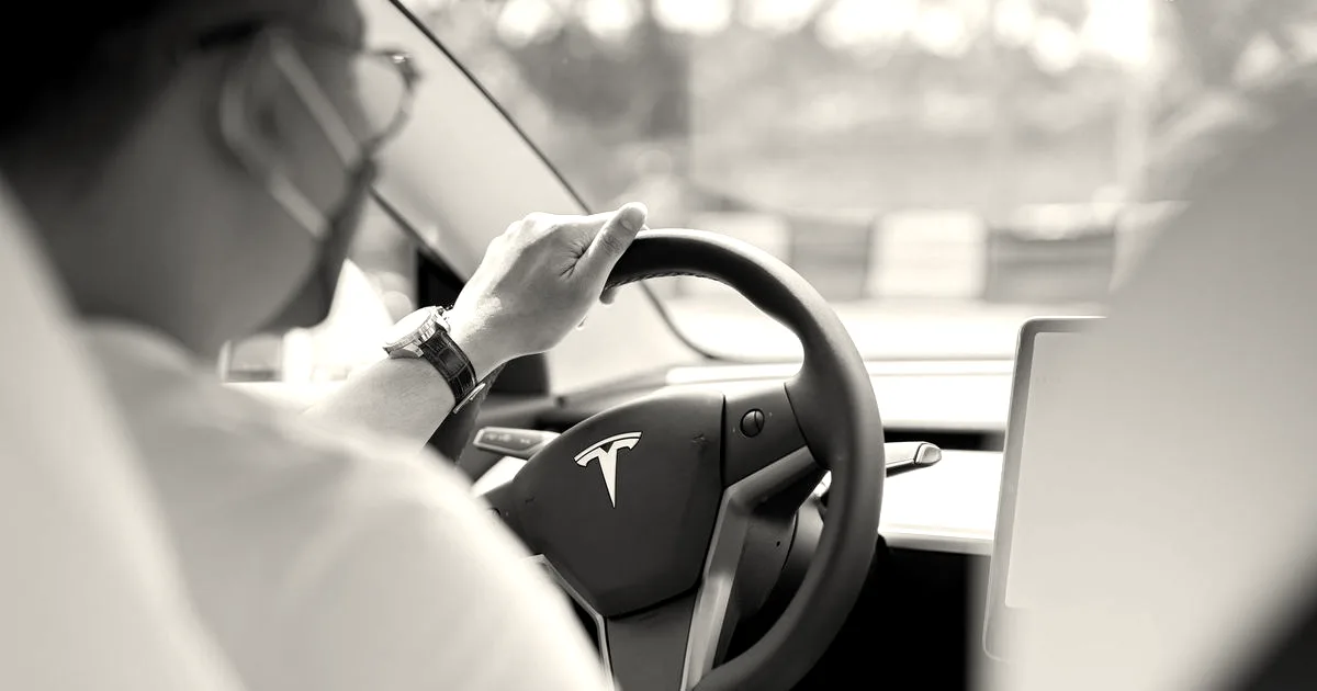 Close-up photo of a person wearing a mask while driving a Tesla, showcasing modern interior and steering wheel.
