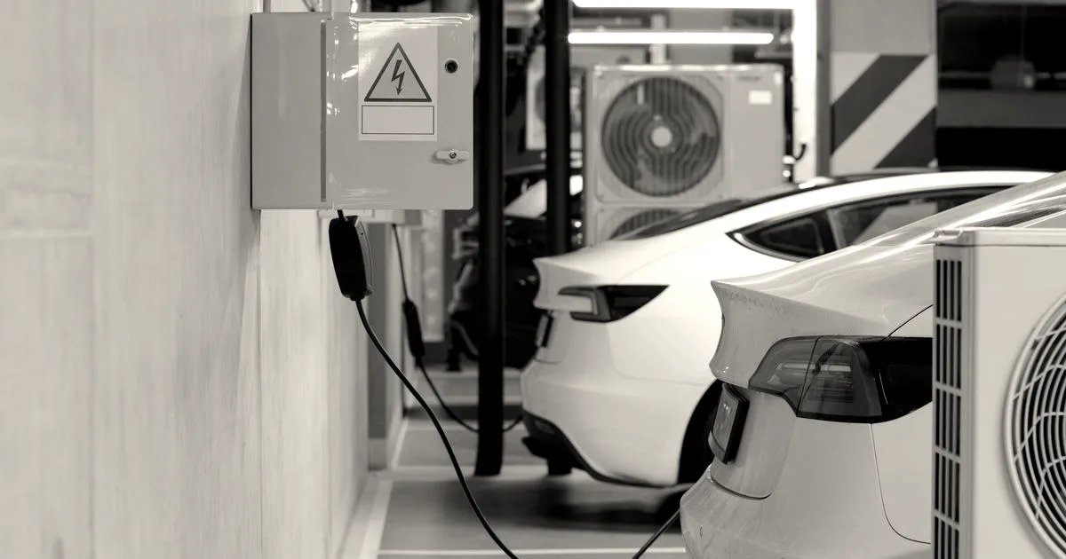 White Tesla Model 3 vehicles parked and charging in an indoor underground electric vehicle station.