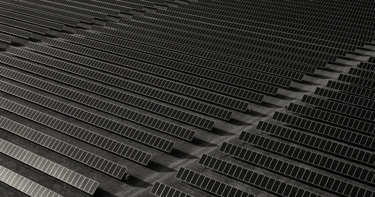 Expansive aerial view of a large ground-mounted solar farm with rows of solar panels extending into the distance.