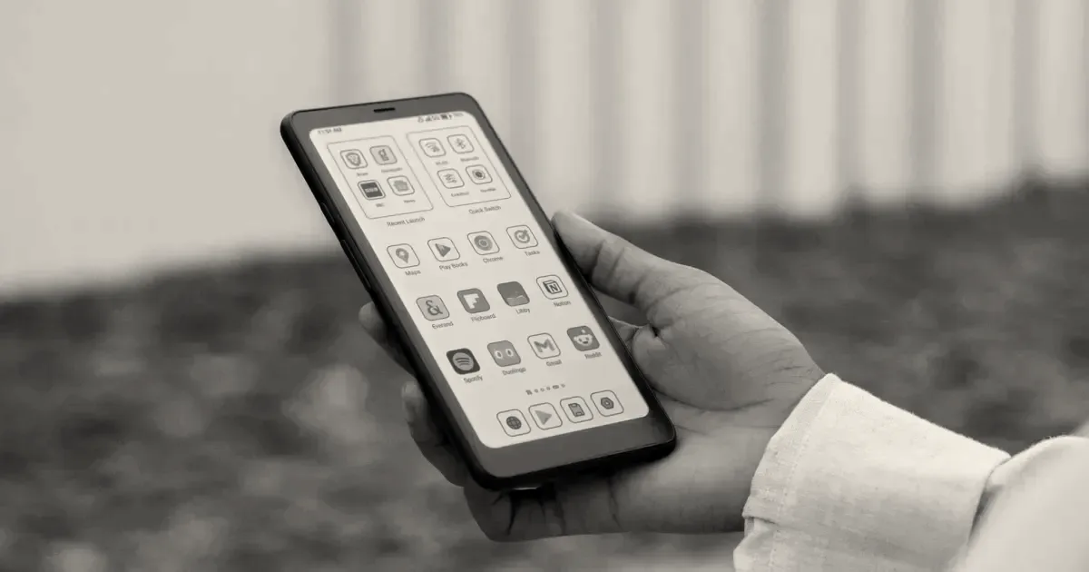 A person holding a black Boox Palma e-reader displaying application icons on its screen.