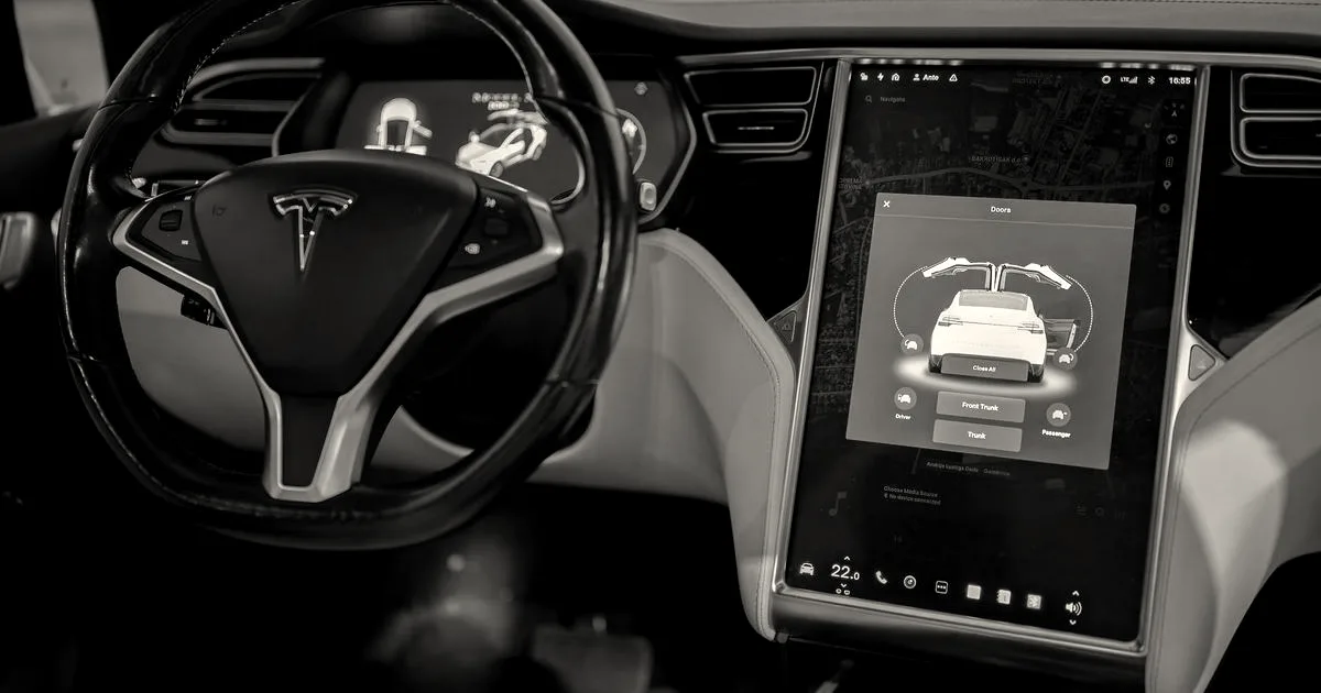 Interior of a Tesla vehicle displaying the center touchscreen showing a Model X with falcon-wing doors open.