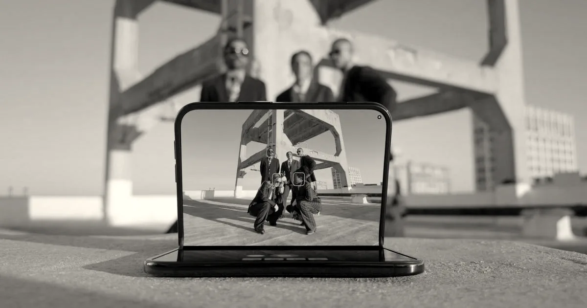 A foldable smartphone set in a tented position on a ledge, displaying a group photo on its screen.