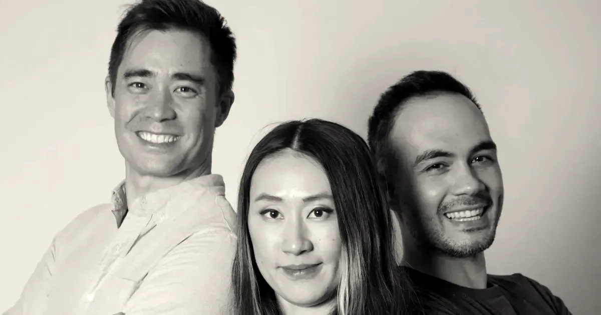 Three co-founders of TypeSafe AI standing together against a plain studio background smiling at the camera.