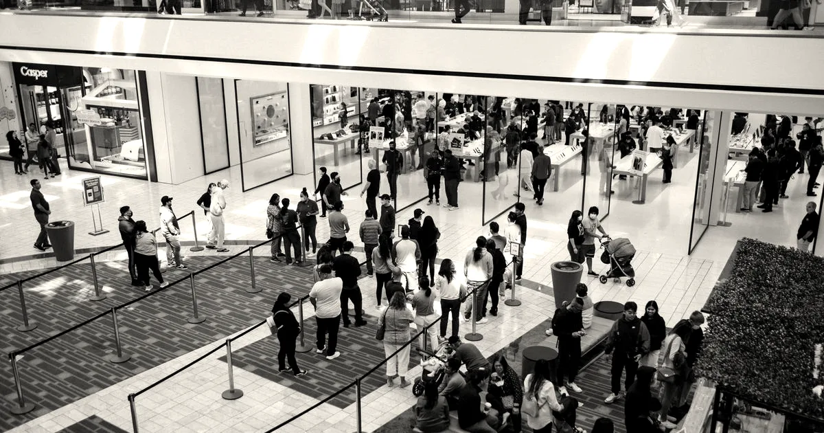 High angle shot of shoppers and crowds queuing outside an Apple Store inside a modern retail mall.