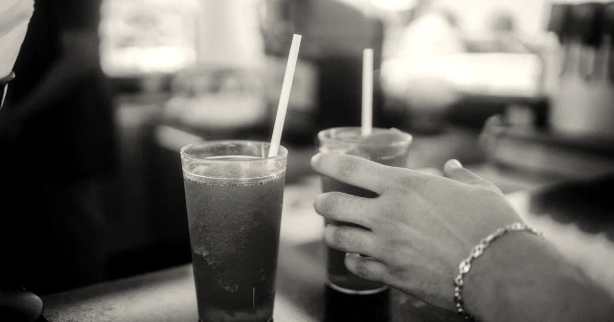A person reaching for a cold red slushie drink in a plastic cup with a straw at a counter.