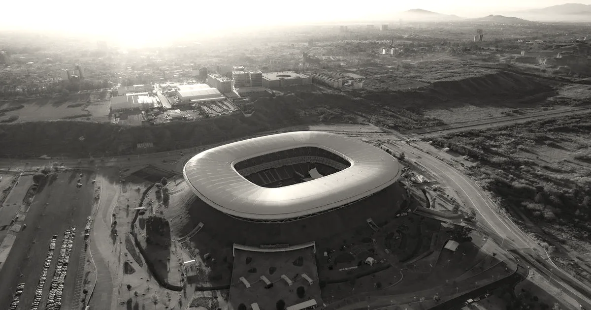 Aerial panoramic view of a modern sports stadium surrounded by landscape at sunset