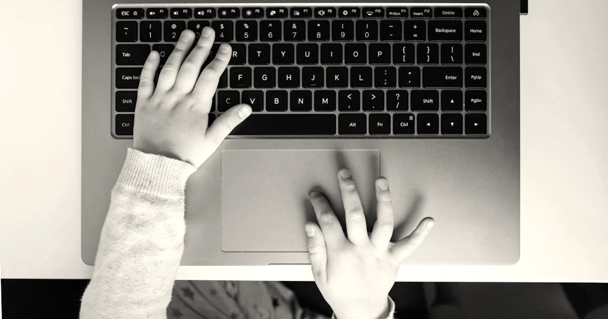 Child's hand on laptop computer keyboard. Trying to log in. Access to information, protection, and usability. Top view