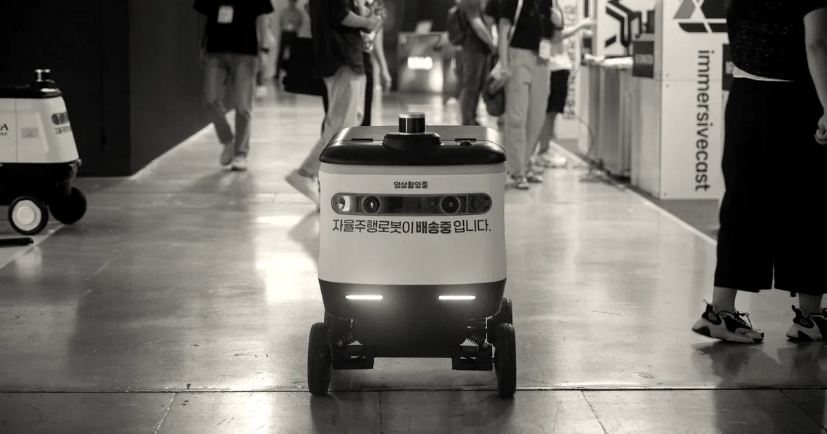 Autonomous delivery robot navigating indoors during a technology event.