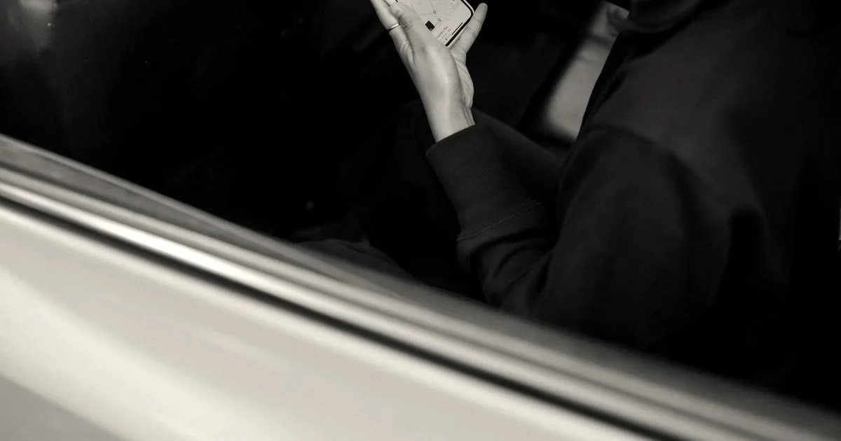 A passenger in the backseat of a yellow cab looking at a smartphone navigation map.