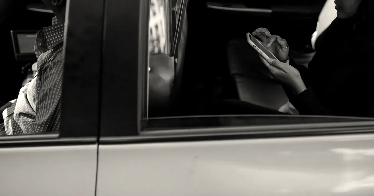 A passenger using a smartphone while sitting in the backseat of a yellow taxi cab