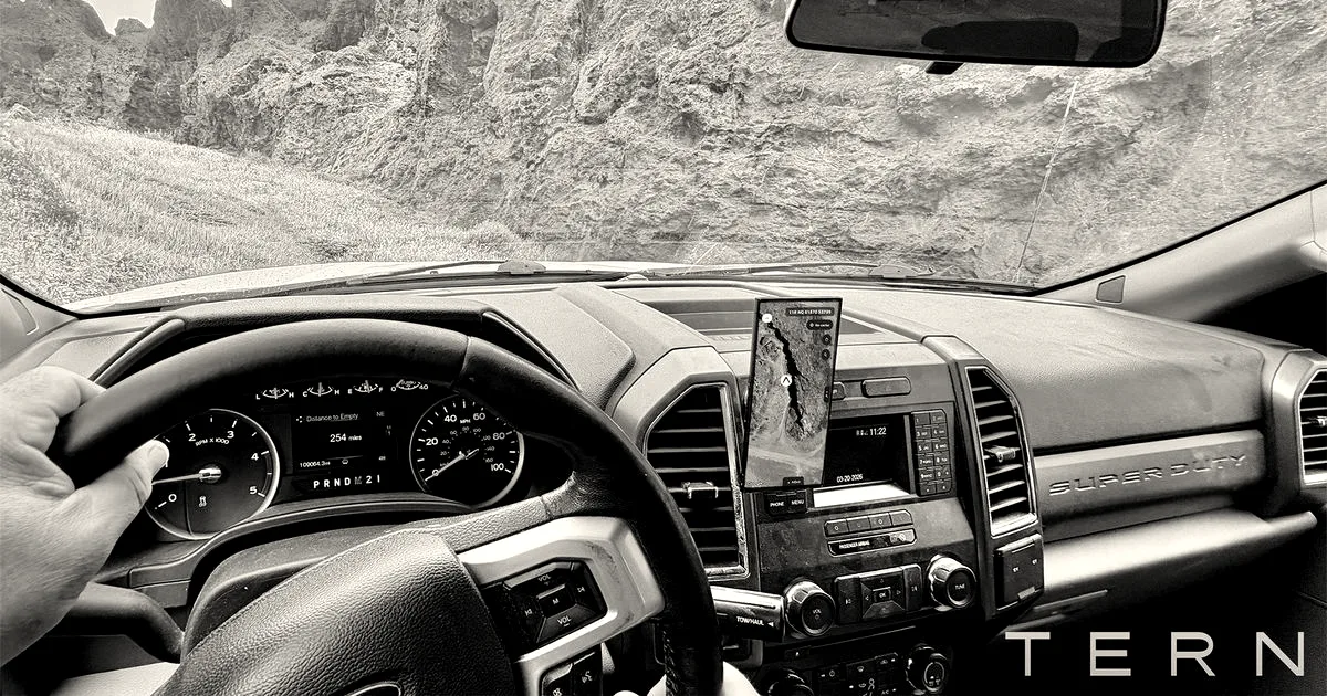 View from the driver's seat of an off-road vehicle navigating rocky terrain with a mounted navigation screen.