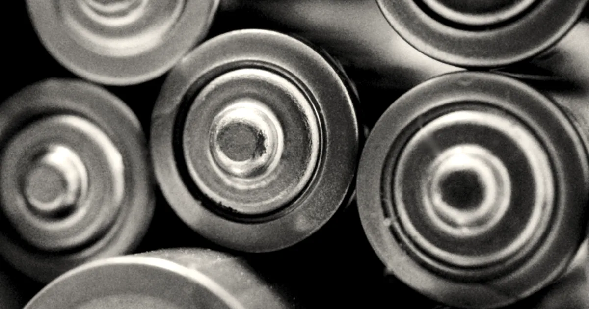 Close-up macro view of the circular tops of multiple cylindrical copper and silver batteries