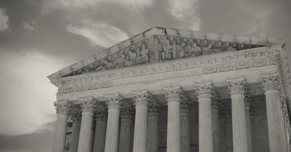 Neoclassical court building exterior featuring grand columns under a cloudy sky.