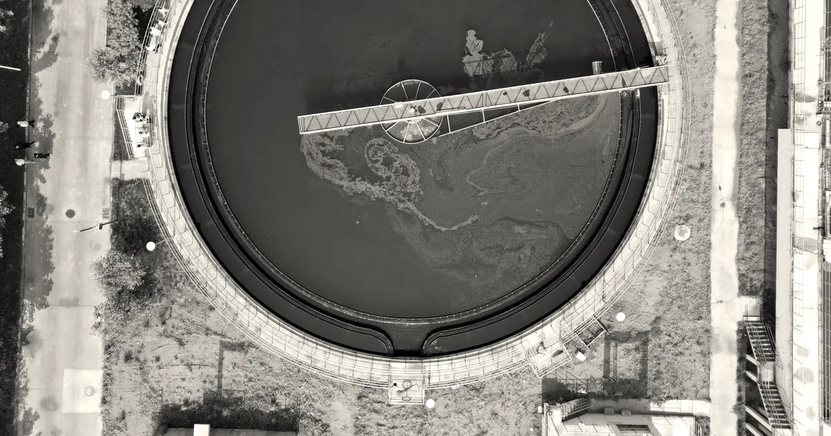 Aerial top-down view of a large circular water treatment tank and clarification bridge at a facility.