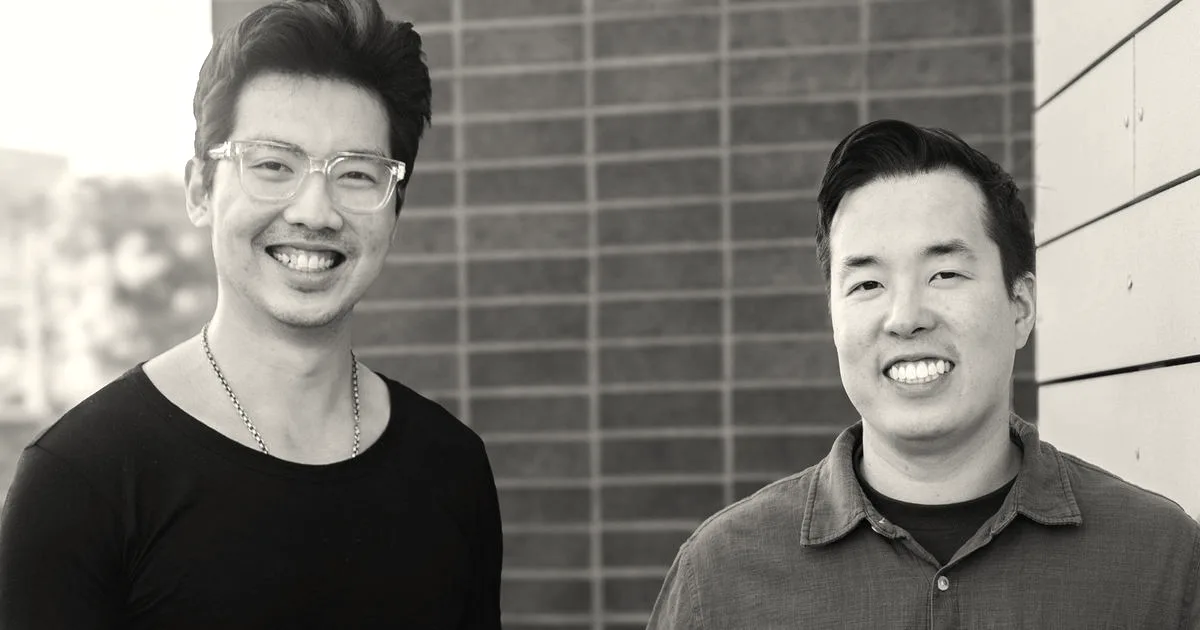 Portrait of the two founders of Vesta smiling outdoors against a brick wall.