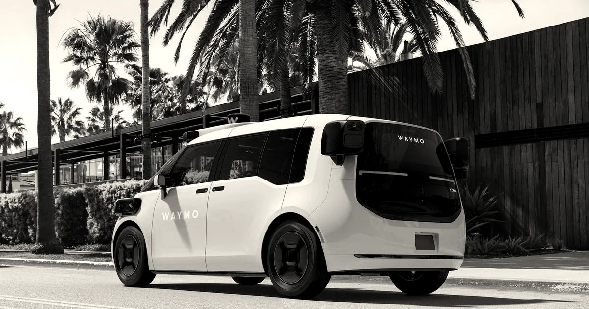 A white autonomous Waymo robotaxi parked on a sunny paved road lined with palm trees.