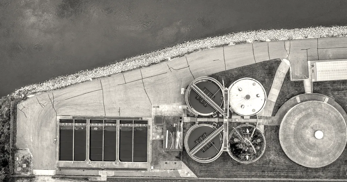 Aerial top-down view of water treatment facility basins and filtration tanks alongside a riverbank.