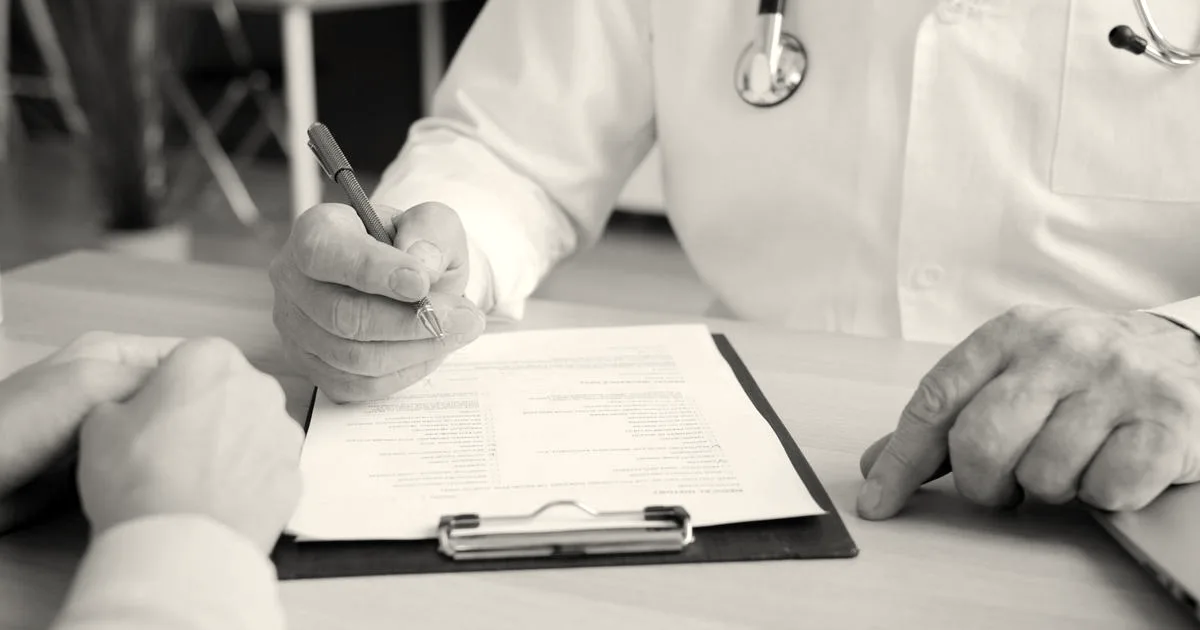 Close-up of doctor and patient reviewing medical documents during consultation.